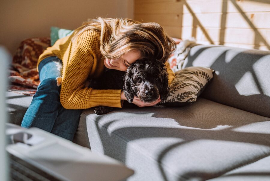 Mujer abrazando a un perro en un sofa